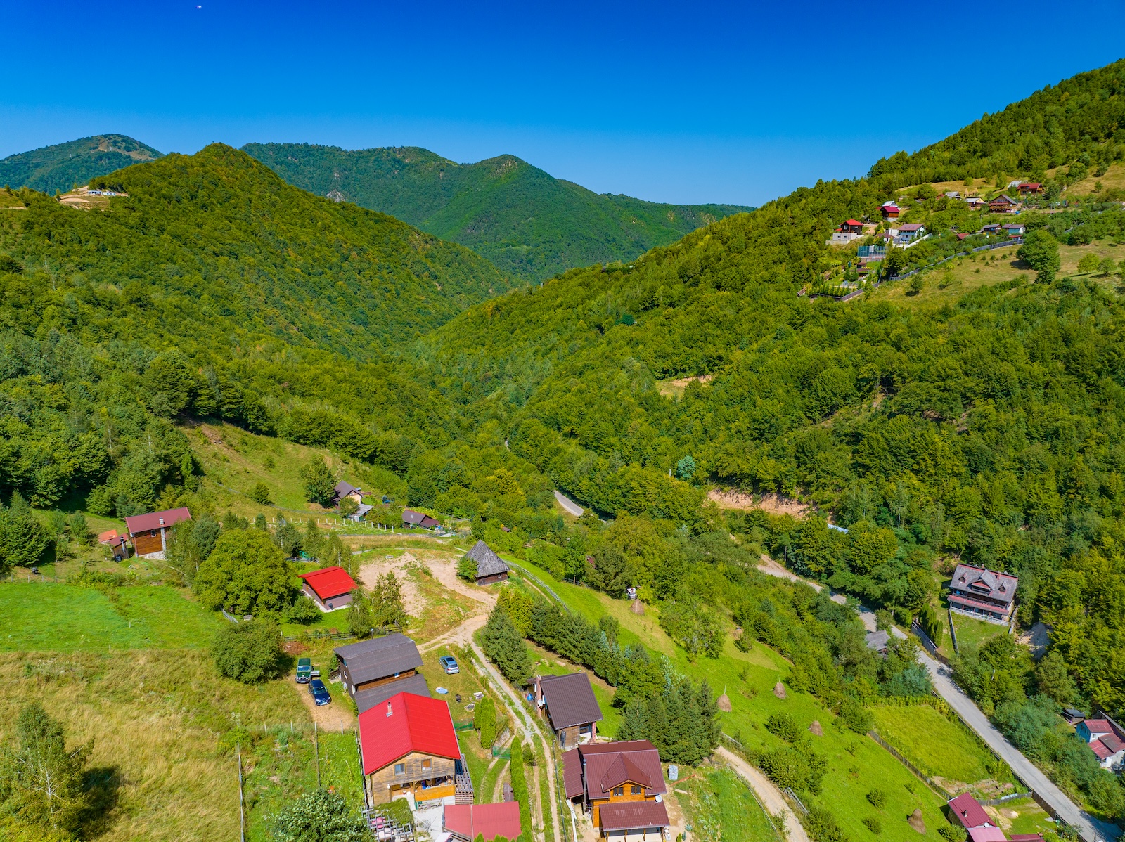 Vedere pe vale cu drum și pădure verde în Someșu Rece